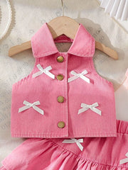Pink denim halter top with white bow accents and gold buttons