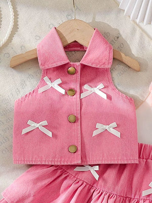 Pink denim halter top with white bow accents and gold buttons