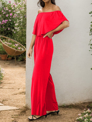 Red off-the-shoulder flounce jumpsuit with wide legs.