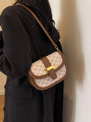 Chic monogrammed flap crossbody bag in rice white with brown trim and gold buckle.