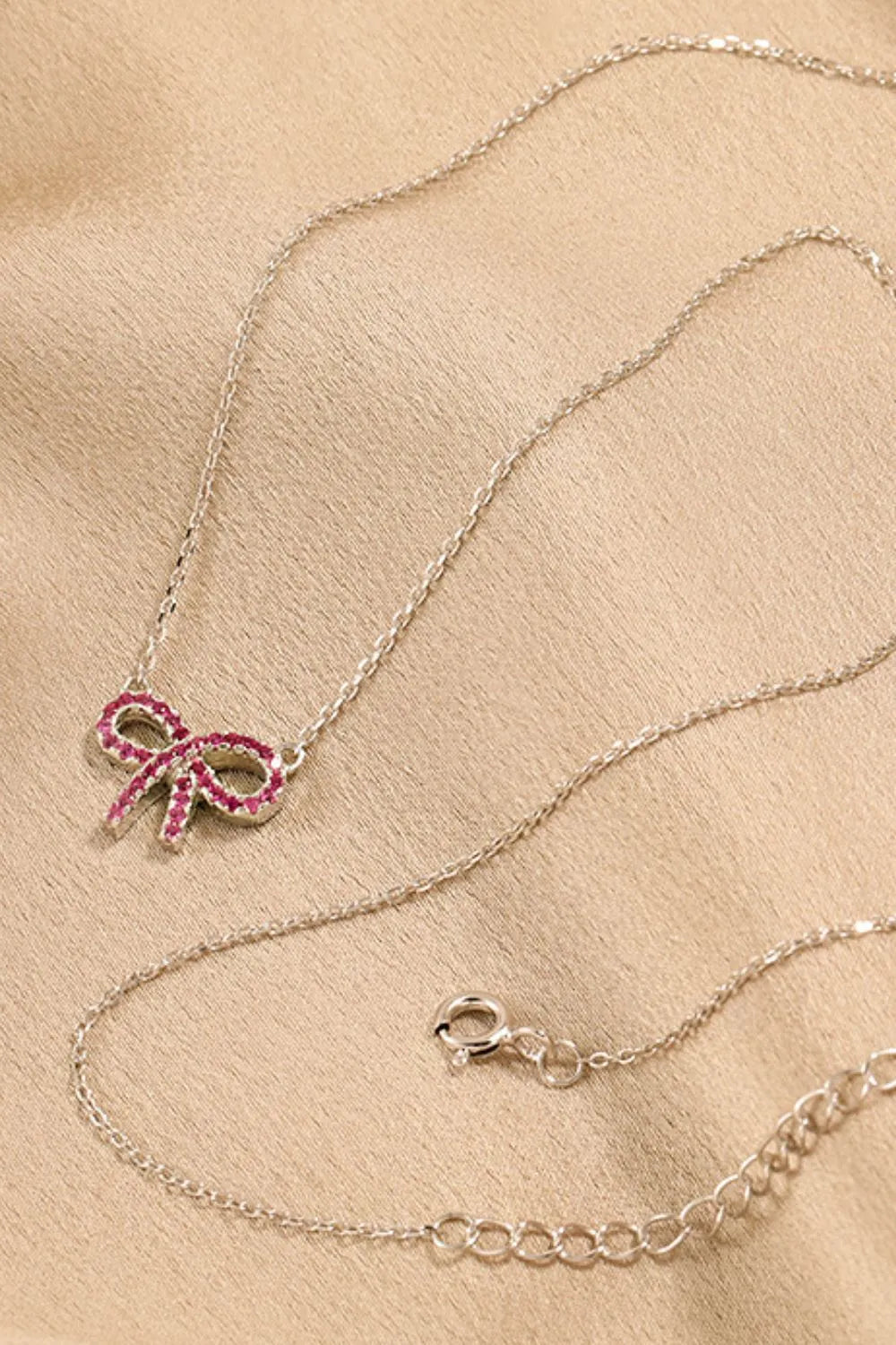 Silver necklace with a ruby-embellished bow pendant and lobster clasp