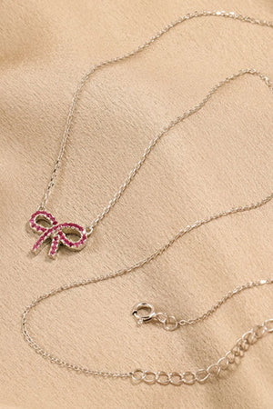 Silver necklace with a ruby-embellished bow pendant and lobster clasp