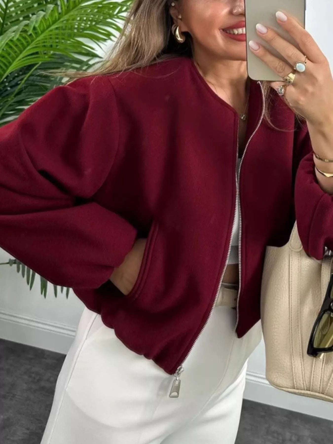 Burgundy zip up cropped bomber jacket with pockets and a round neckline.