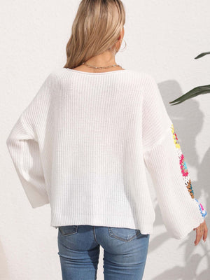 White knit sweater with colorful granny square sleeves and a boat neck.