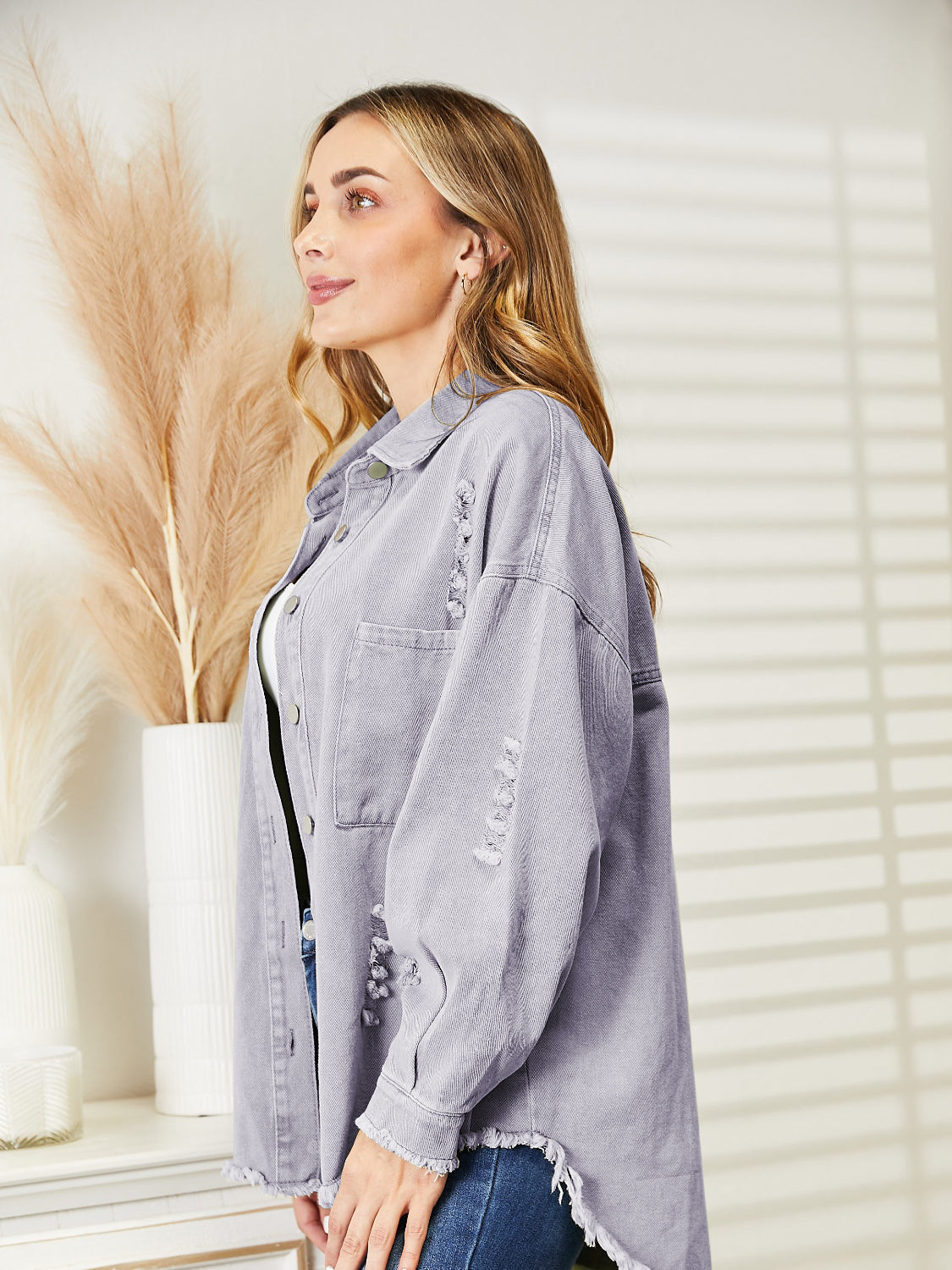 Distressed denim overshirt with raw hem in lilac, featuring button front and frayed details.