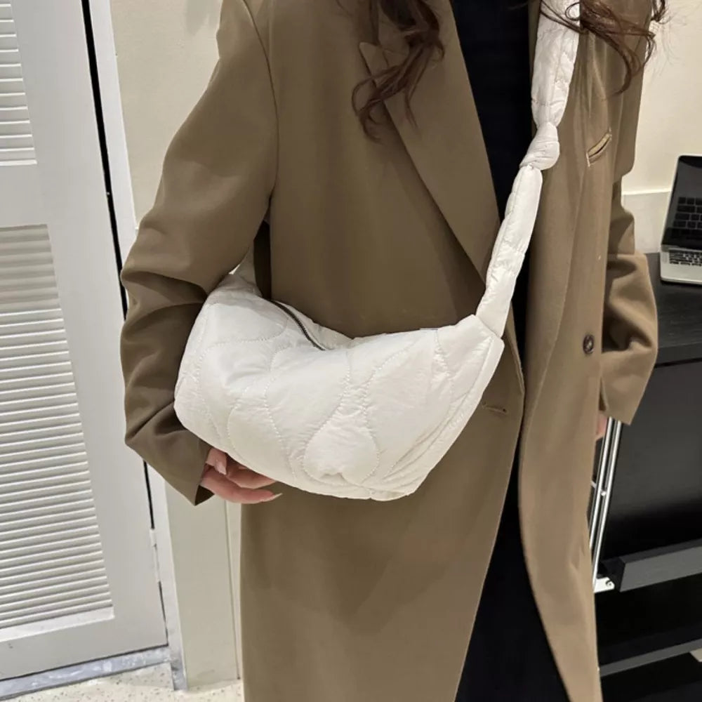 White puffy quilted crossbody bag with knotted strap and abstract pattern.