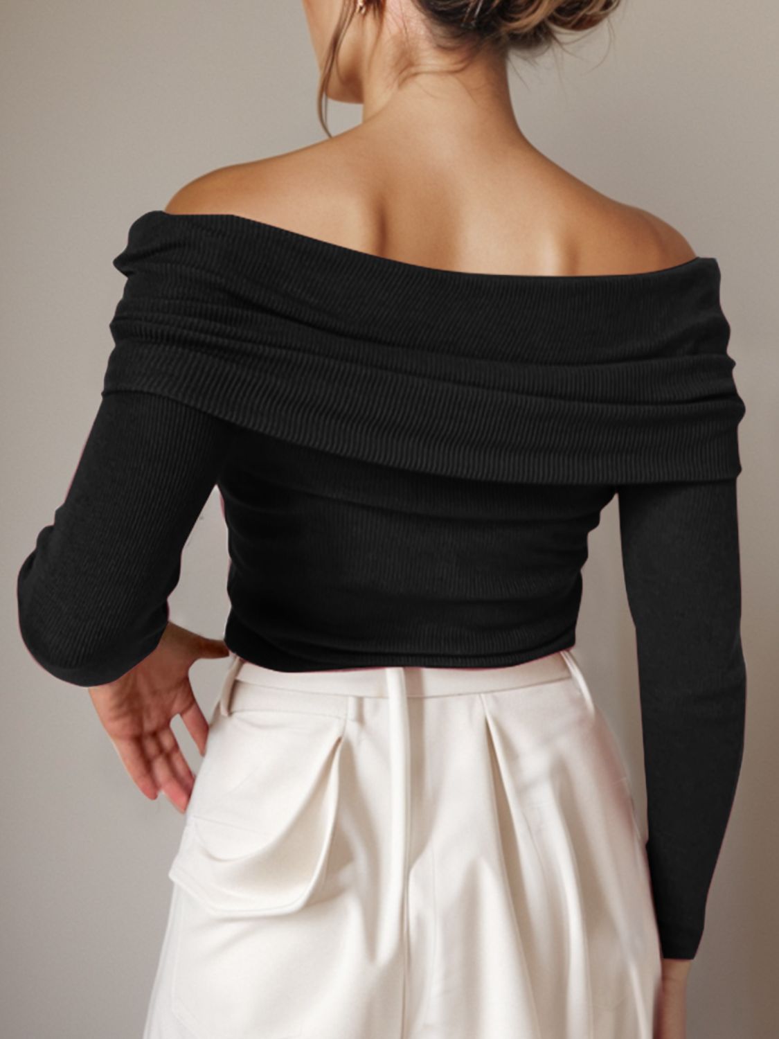 Black knit off-the-shoulder sweater with long sleeves and draped neckline.