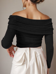 Black knit off-the-shoulder sweater with long sleeves and draped neckline.