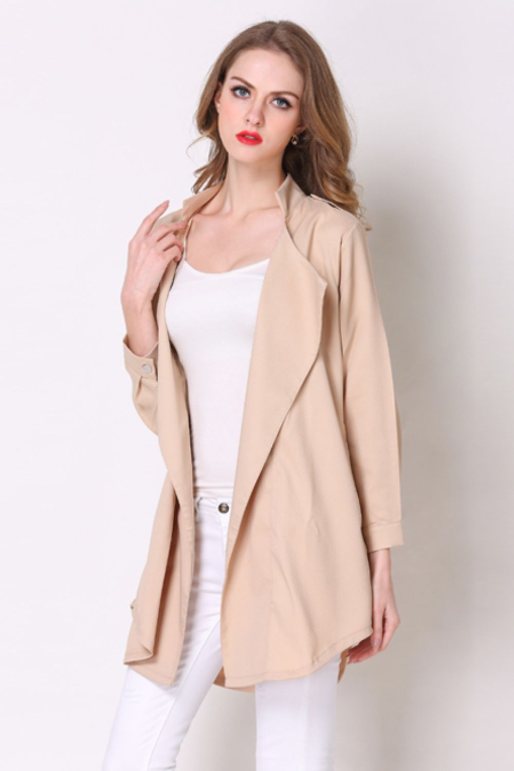 Tan drape-front trench coat with shoulder detailing and buttoned cuffs.