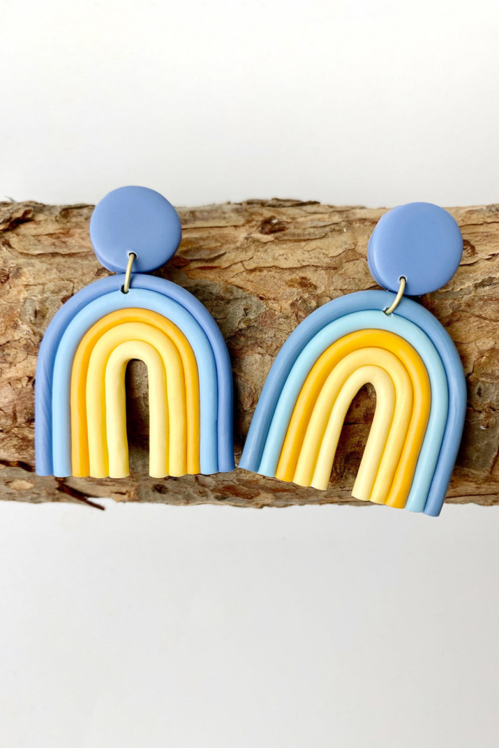 Clay rainbow arch earrings in dusty blue and yellow with a round stud.