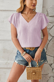Lilac textured v-neck blouse with pleated cap sleeves.