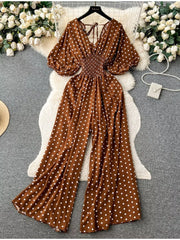 Caramel polka dot smocked wide-leg romper with V-neck and tie back.