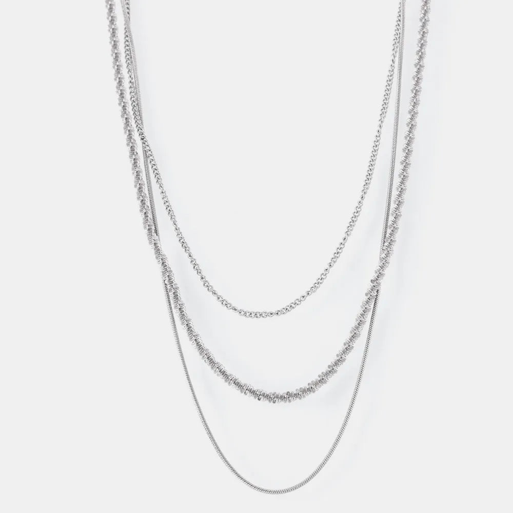 Delicate three-strand silver crystal necklace with layered chains and textured details.