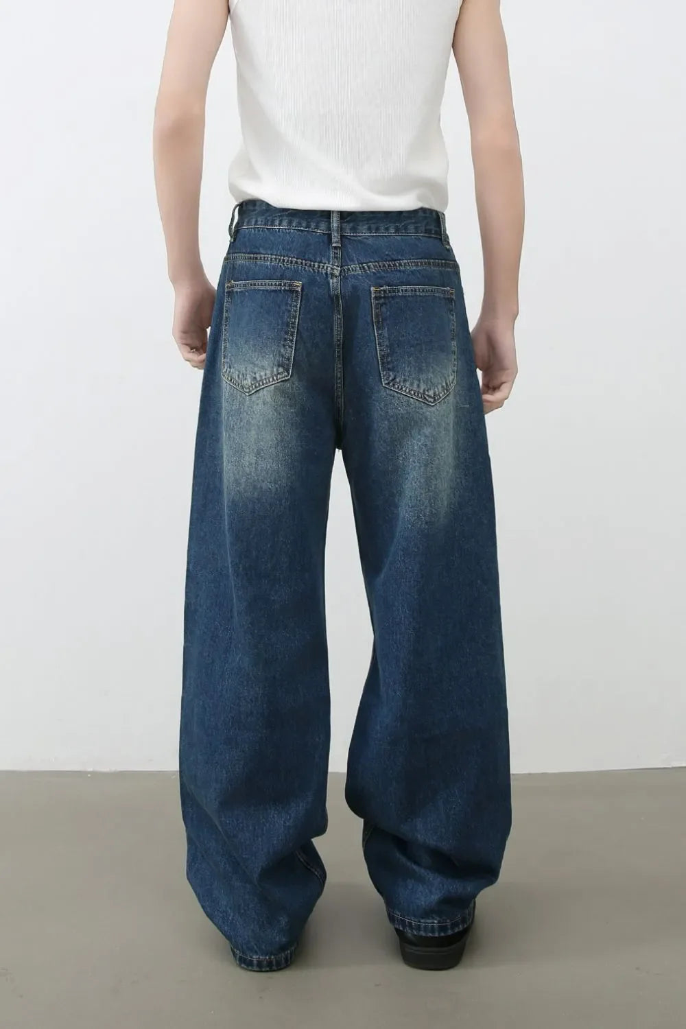 Oversized ripped denim jeans in medium wash with wide-leg silhouette and distressed details.