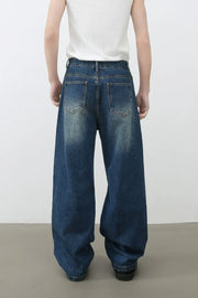 Oversized ripped denim jeans in medium wash with wide-leg silhouette and distressed details.