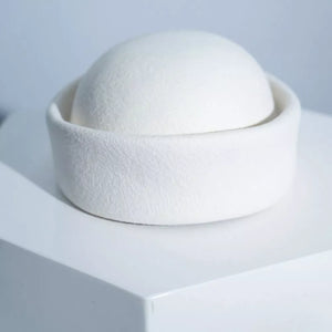 Elegant white wool pillbox hat with a rounded crown and a wide brim.