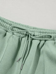 Sage cotton joggers with drawstring waist and silver-tipped ties.