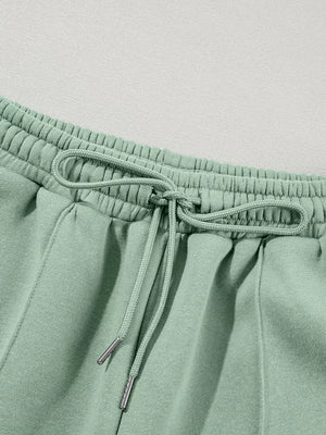 Sage cotton joggers with drawstring waist and silver-tipped ties.