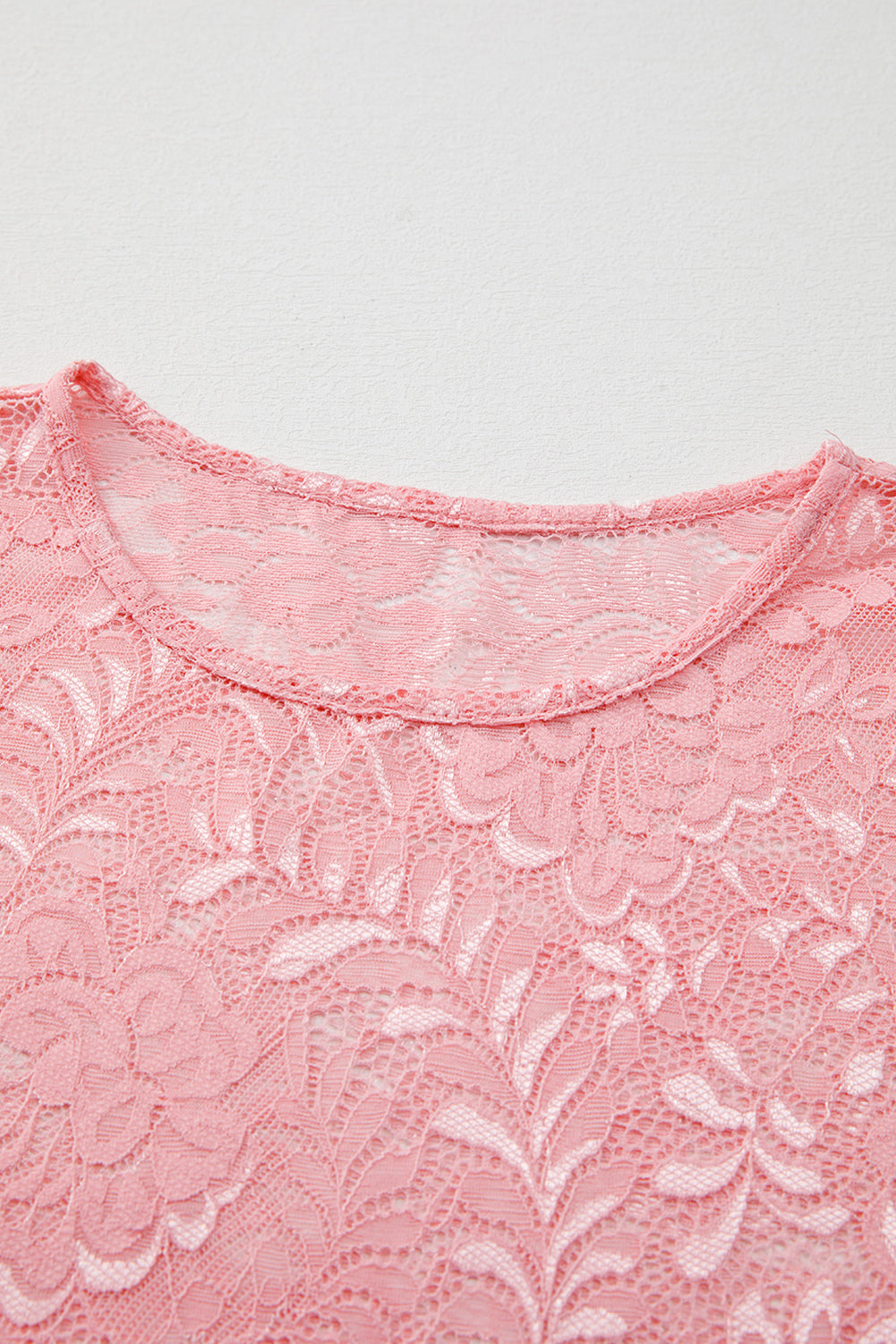 Dusty pink lace blouse with a round neckline and intricate floral pattern.