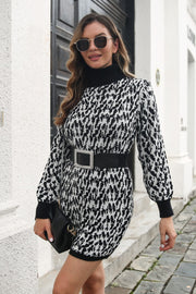 Black houndstooth knit turtleneck mini dress with long sleeves and a black jeweled belt.