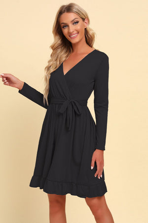 Black wrap dress with long sleeves, tie waist, and ruffled hem.