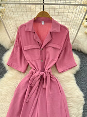 Pink belted wide-leg maternity jumpsuit with pockets and button front.