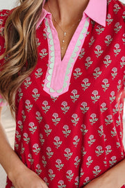 Red floral mini dress with pink and green trim, V-neck, and button details.