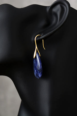 Gold dangle earrings with a teardrop sapphire stone.
