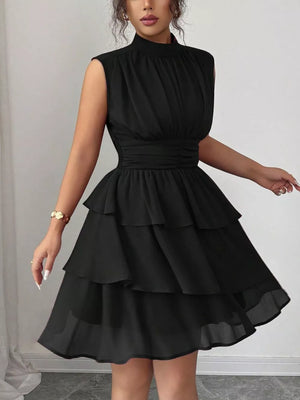 Black sleeveless ruffled tiered dress with a high neckline and cinched waist.
