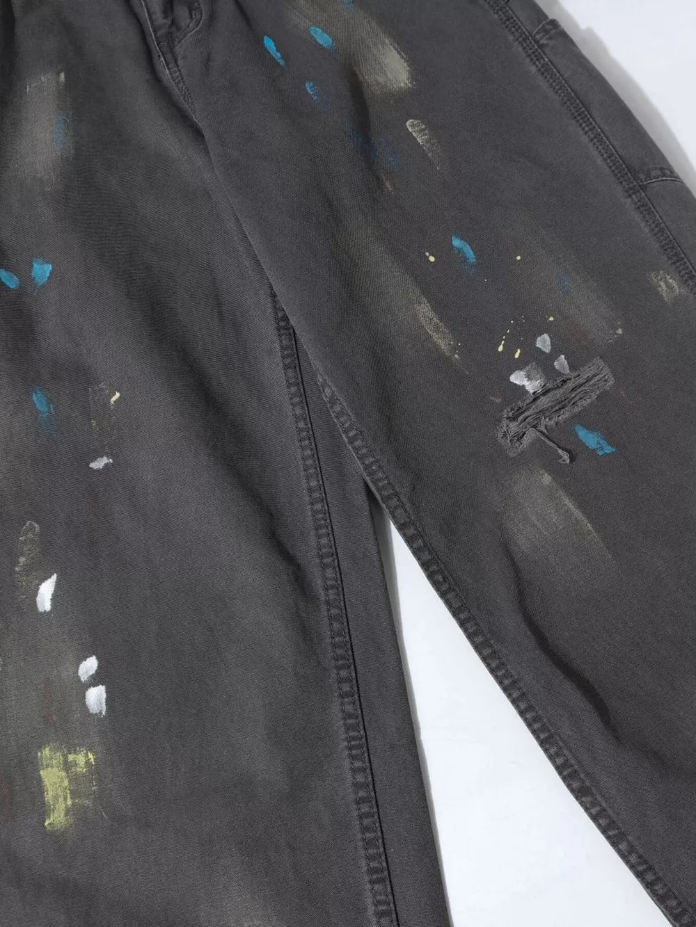 Distressed charcoal wide-leg sweatpants with paint splatter detail and visible stitching.