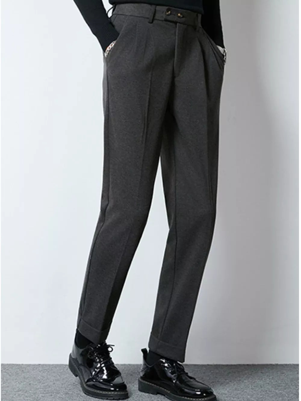 Men's dark gray tailored pleated dress pants with cuffed hems.