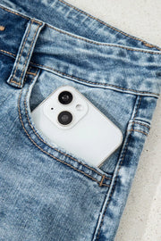Distressed denim flare jeans with a white smartphone in the pocket