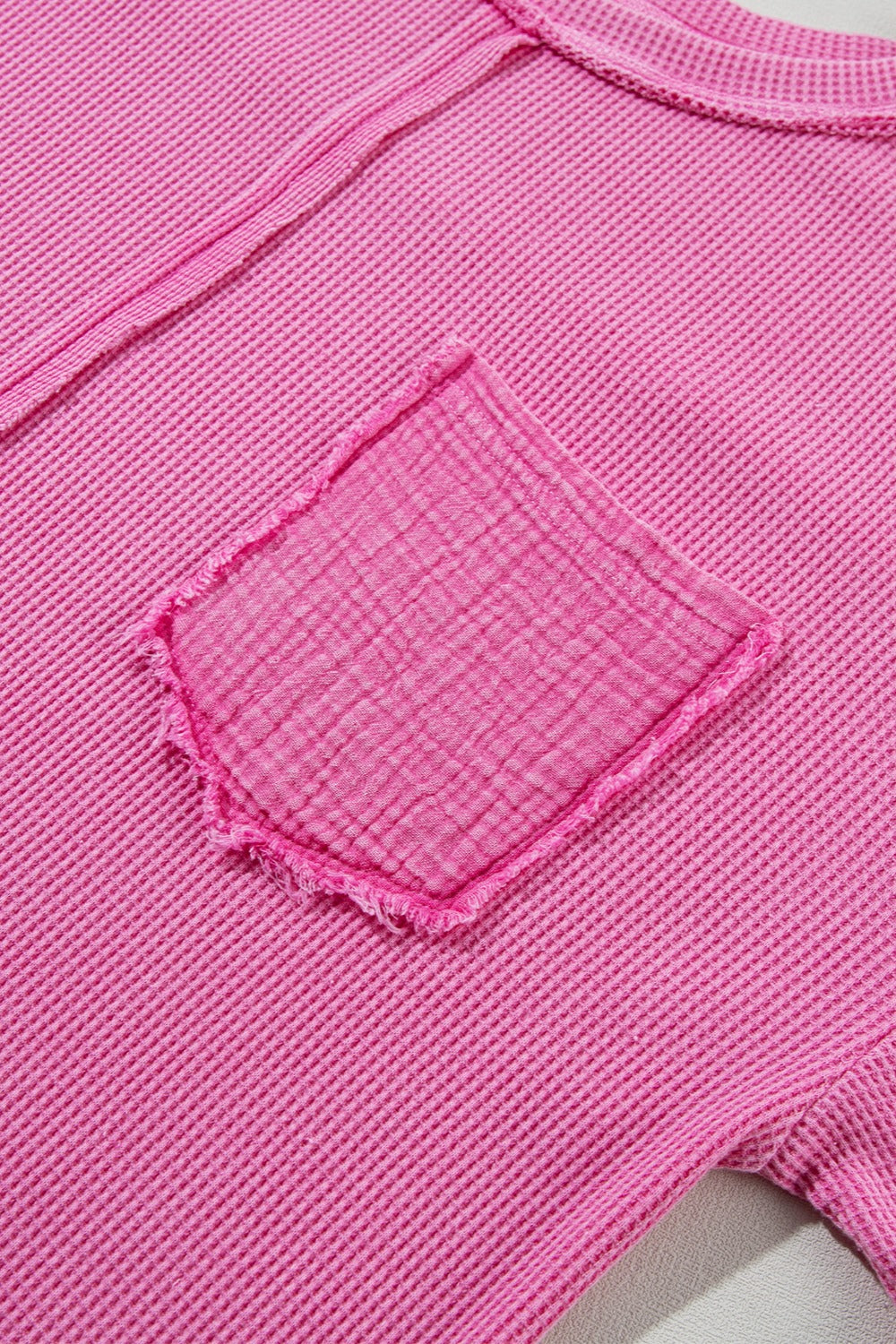 Fuchsia pink waffle knit top with raw seam detail and a deconstructed pocket.