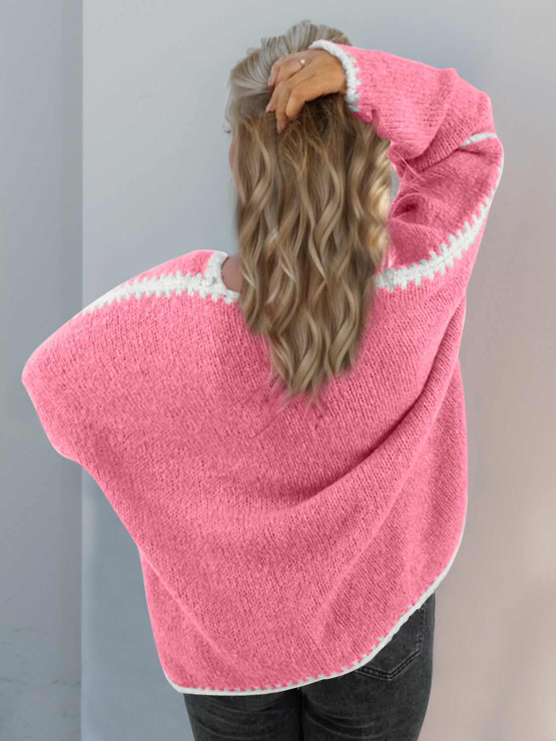 Pink oversized knit cardigan with contrast white stitching detail on sleeves and neckline.