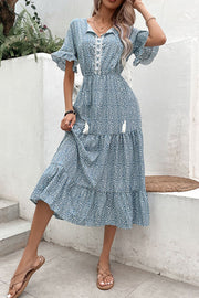 Light blue floral midi dress with tiered skirt, ruffled sleeves, and tassel details.