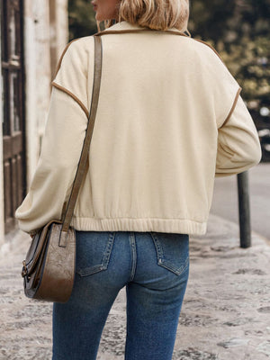 Cream fleece track jacket with contrast trim and elasticated hem, worn with jeans.