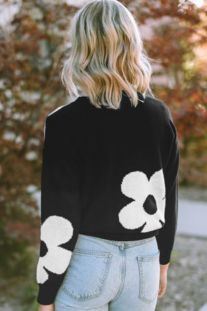 Black acrylic crewneck sweater with white floral intarsia pattern on back and sleeves.