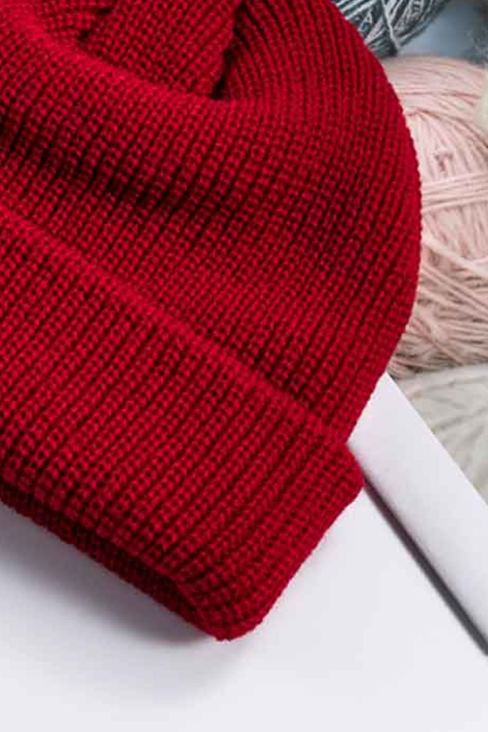 Red ribbed knit beanie with a turn-up cuff, acrylic material.