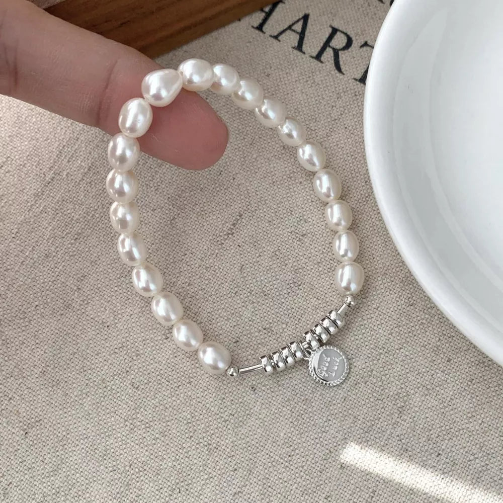 Delicate freshwater pearl bracelet with silver beads and a round charm.