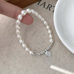 Delicate freshwater pearl bracelet with silver beads and a round charm.