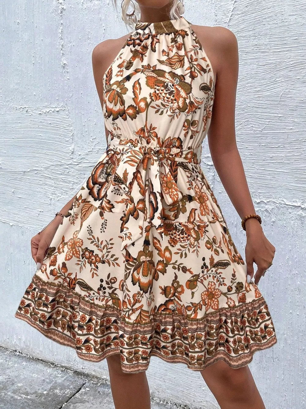 Floral print halter dress with tie waist in tan and burnt coral with ruffled hem.
