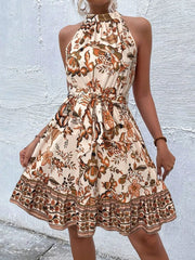 Floral print halter dress with tie waist in tan and burnt coral with ruffled hem.