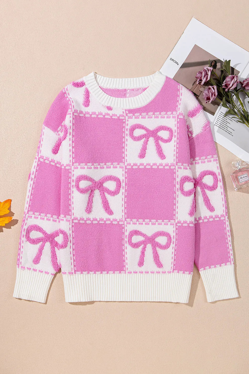Fuchsia pink and white checkered bow jacquard knit sweater with crewneck and ribbed trim.