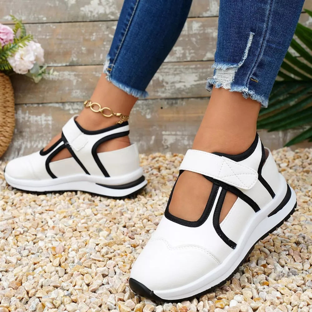 White Mary Jane cutout sneakers with black contrast trim and hook-and-loop straps.