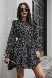 Black dot print dress with ruffle trim, long sleeves, and cinched waist.
