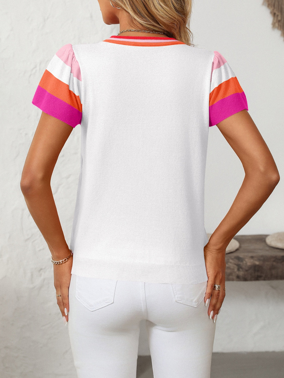 White knit top with colorblock flutter sleeves in pink, orange, and sky blue.