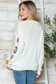 White knit sweater with crochet granny square sleeve details, casual style.