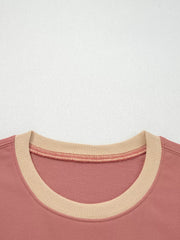 Dusty pink sweatshirt with contrast tan ribbed neckline and exposed seam detail.