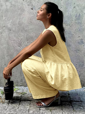 Yellow peplum hem two-piece set with button detail, wide leg pants, and sleeveless top.