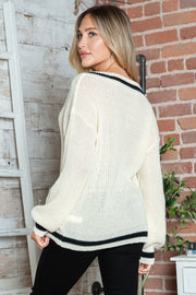 Cream ribbed knit sweater with black stripe trim and pearl details, V-neck.